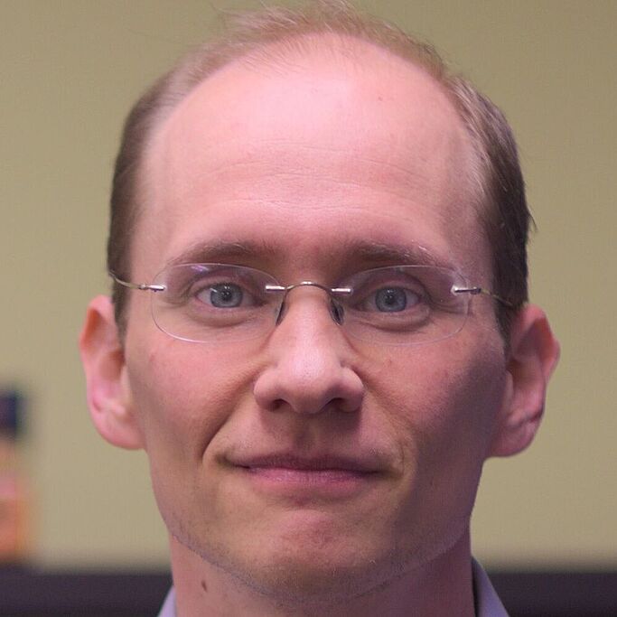 Portrait of a man with short hair and shirt against a neutral background. It is Jonathan Katz.