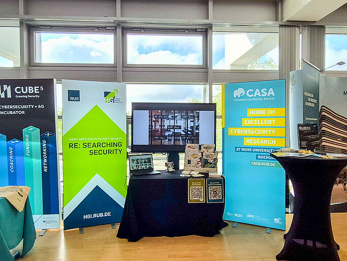 There are several advertising banners and a standing table in a bright room with large windows. This is the CASA/HGI stand at the ITS.Connect.