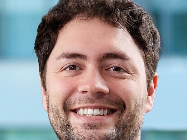 Porträt eines Mannes mit kurzem, lockigem Haar und Bart vor unscharfem Hintergrund. Es handelt sich um Jonas Haferkamp.