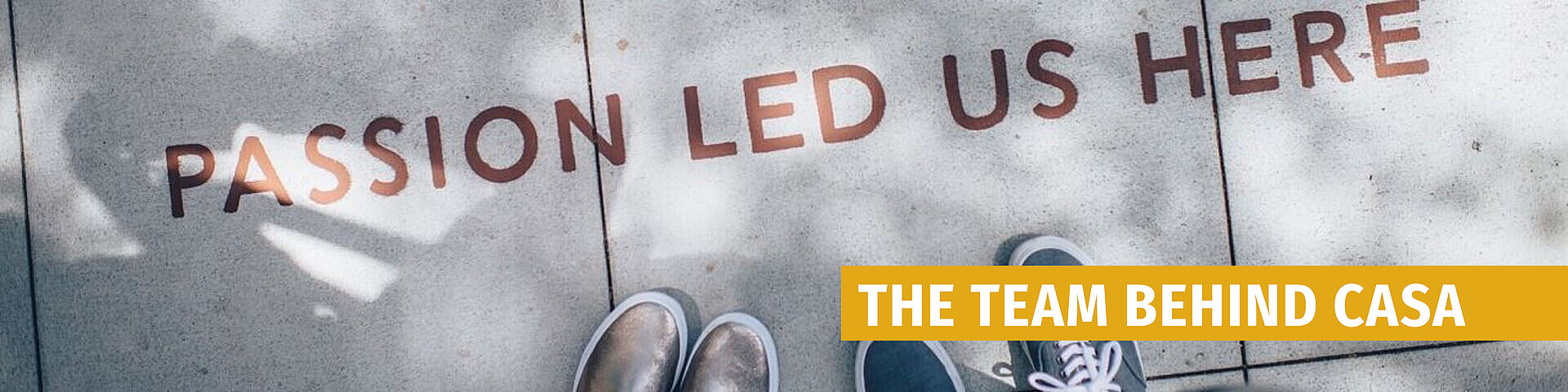 Graffiti on a wall reading 'PASSION LED US HERE' with a yellow bar containing the text 'THE TEAM BEHIND CASA'