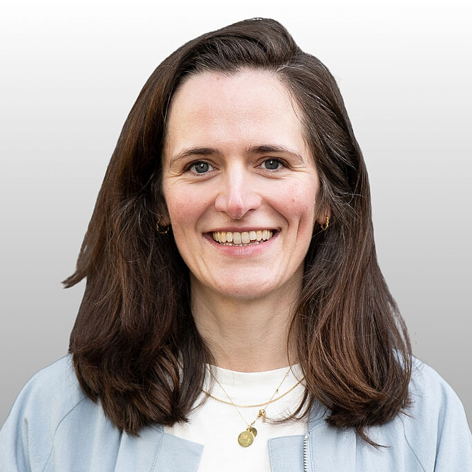 Frau mit schulterlangen braunen Haaren, weißem Hemd und goldener Halskette vor hellem Hintergrund. Es handelt sich um Johanna Luttermann.