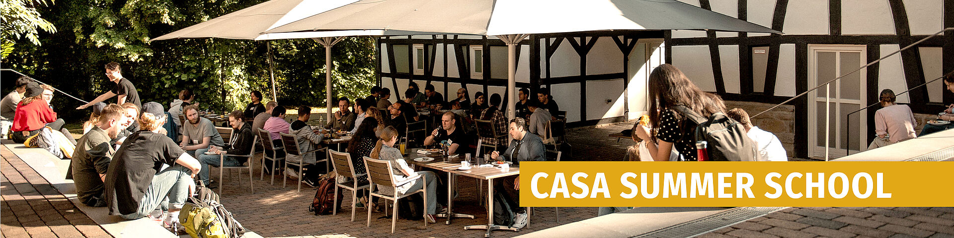 People sitting at tables outdoors in front of a half-timbered building